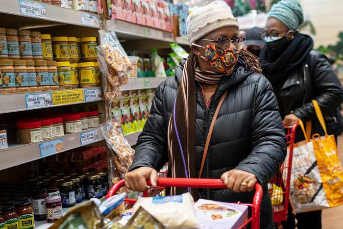 A woman wearing a mask moves her shopping cart December 3, 2020 in a Trader Joe's supermarket in New York City.