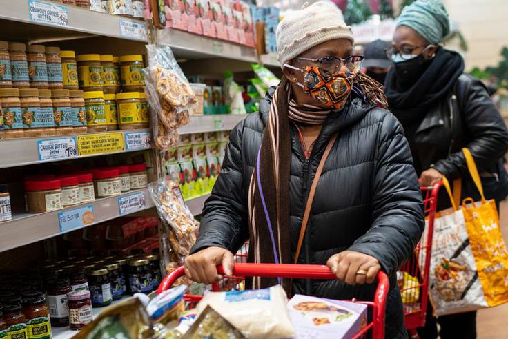 A woman wearing a mask moves her shopping cart December 3, 2020 in a Trader Joe's supermarket in New York City.