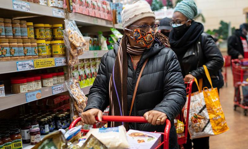 A woman wearing a mask moves her shopping cart December 3, 2020 in a Trader Joe's supermarket in New York City.