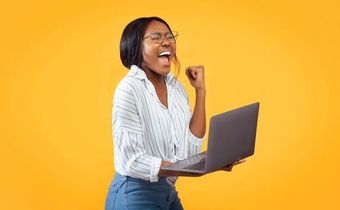 A person showing excitement while holding a laptop