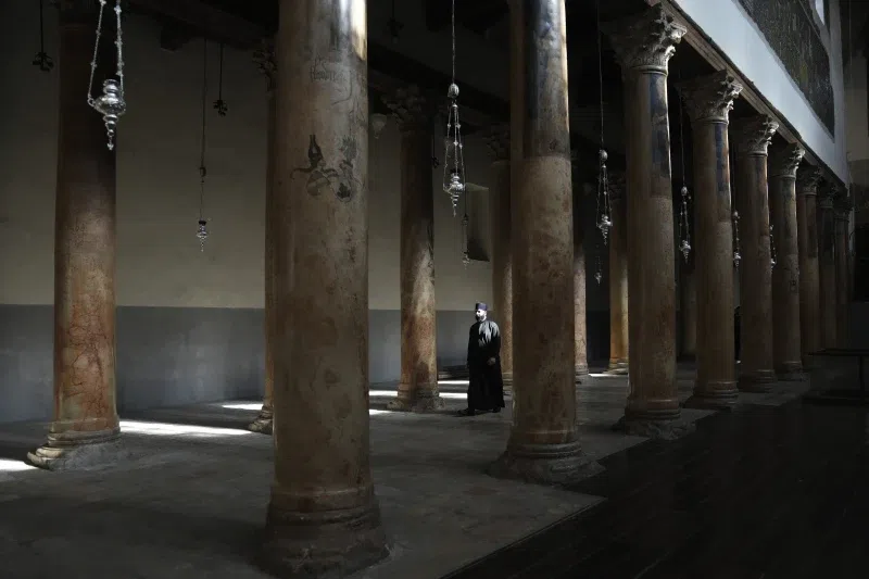 A priest walks in the Church of the Nativity, where Christians believe Jesus Christ was born, ahead of Christmas in the West Bank city of Bethlehem, Tuesday, Dec. 17, 2024. (AP Photo/Mahmoud Illean)
