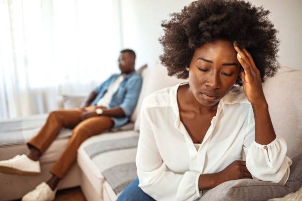 Sad pensive young girl thinking of relationships problems sitting on sofa