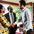 An African man in his thirties, warmly greeted by his in-laws in a beautifully decorated living room