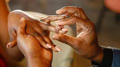 A photo of a couple exchanging wedding rings.