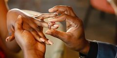 A photo of a couple exchanging wedding rings.