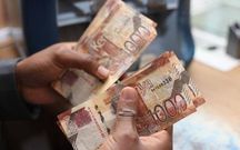 A person holding Kenyan currency