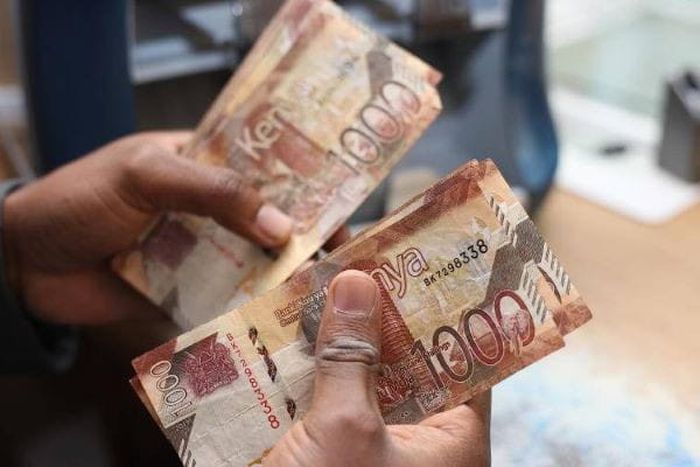 A person holding Kenyan currency