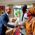 An African man in his thirties, warmly greeted by his in-laws in a beautifully decorated living room