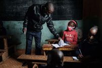 A teacher assists a student of Miracle and Victory Children Centre, a private primary school for orphans, during a class as schools reopen after a 6 weeks break following the directive by Kenyan President Uhuru Kenyatta's to curb the spread of the Covid-19 coronavirus, in Kibera slum, Nairobi, on May 10, 2021. (Photo by YASUYOSHI CHIBA/AFP via Getty Images)