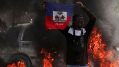 A demonstrator holds up a Haitian flag during protests demanding the resignation of Prime Minister Ariel Henry in Port-au-Prince, Haiti, March 1, 2024 [AP}