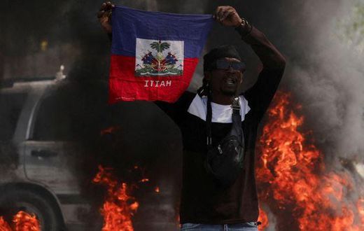 A demonstrator holds up a Haitian flag during protests demanding the resignation of Prime Minister Ariel Henry in Port-au-Prince, Haiti, March 1, 2024 [AP}