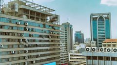 An AI-generated image of urban landscape in Nairobi, Kenya featuring modern high-rise buildings with visible air conditioning vents The scene depicts a clear sky and bustling