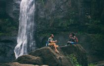 A man and woman near waterfall. Photo by Nandhu Kumar from Pexels.
