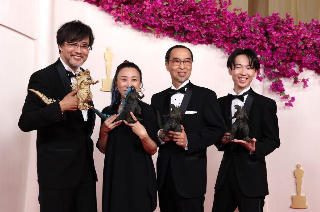Members of the "Godzilla Minus One" crew carried miniature Godzilla statues wearing bow ties.