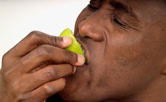 Close-up of a man biting into a lemon half