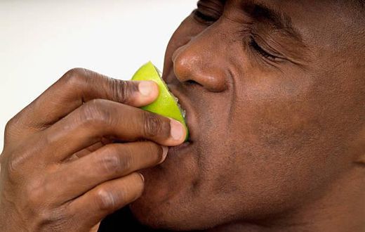 Close-up of a man biting into a lemon half