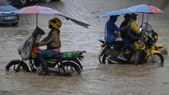 Boda boda riders wading through floods