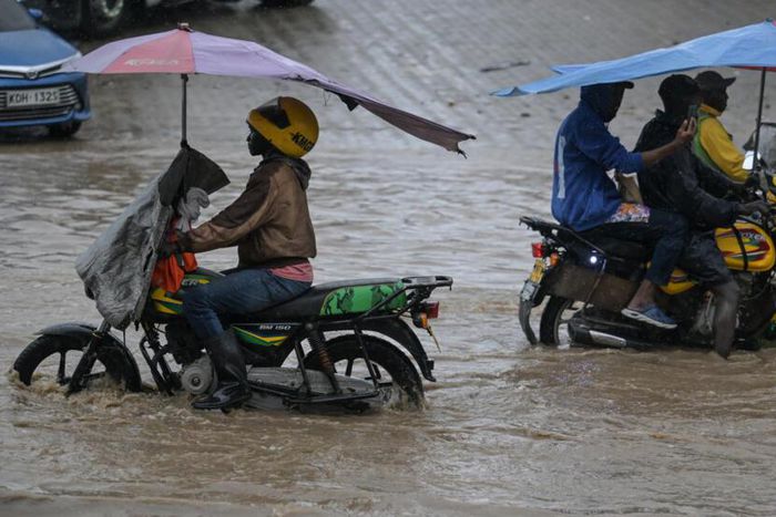 Boda boda riders wading through floods