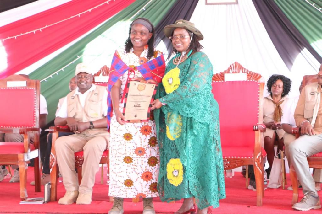 Susan Mutua from Elephant Cooporation receives a certificate from CS Peninah Malonza after the organisation adopted an elephant during the 2023 Tembo Naming Festival at the Amboseli National Park