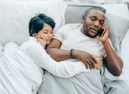 Man speaking on phone next to a sleeping lady