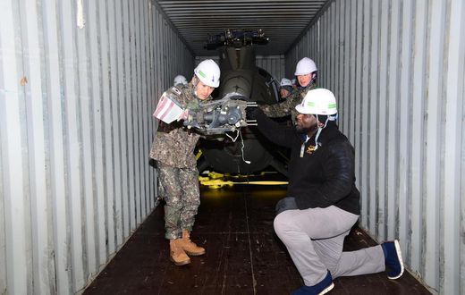 South Korean and US military personnel inspect a 500MD helicopter loaded on a container It is one of six retired helicopters to be donated to Kenya for UN peacekeeping missions