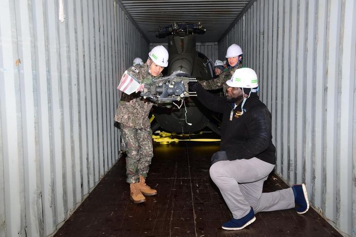 South Korean and US military personnel inspect a 500MD helicopter loaded on a container It is one of six retired helicopters to be donated to Kenya for UN peacekeeping missions