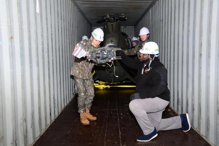 South Korean and US military personnel inspect a 500MD helicopter loaded on a container It is one of six retired helicopters to be donated to Kenya for UN peacekeeping missions