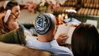 A Jewish family gathered round reading together [Image Credit: RDNE]