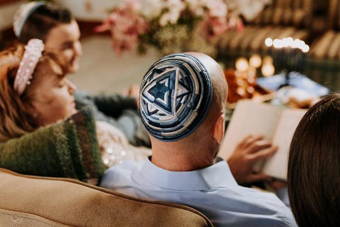 A Jewish family gathered round reading together [Image Credit: RDNE]