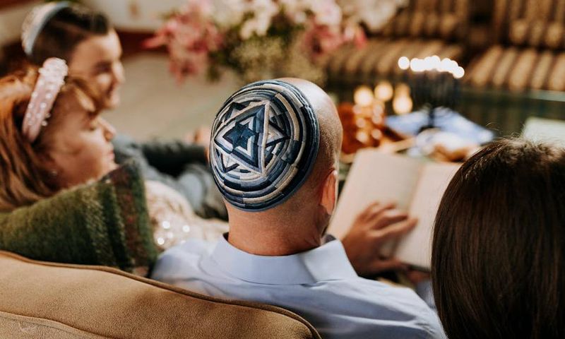 A Jewish family gathered round reading together [Image Credit: RDNE]
