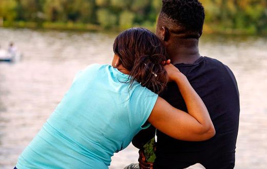 A lady and a man sitting by the river