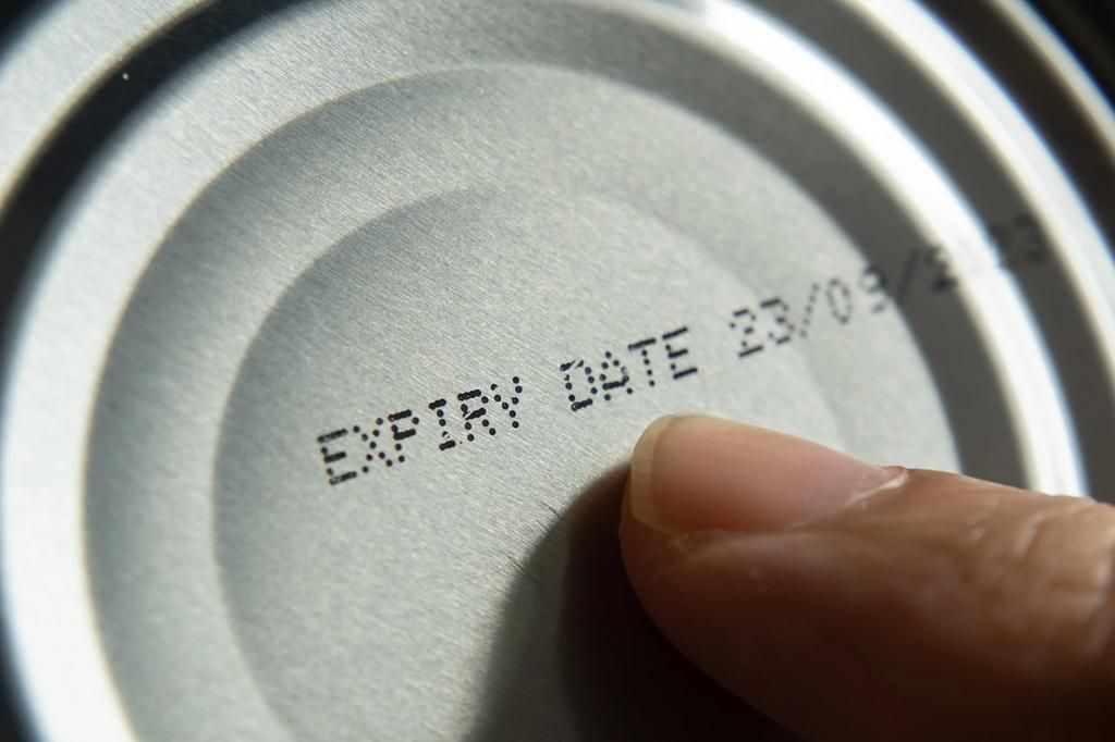 A person pointing at the expiry date on a can [Getty Images]