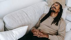 Pensive black man lying on couch [Photo: Alex Green]