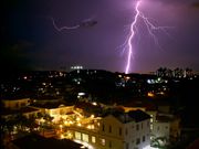 Lightning illuminates the horizon behind a Malaysian cityscape.