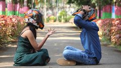 Photo of a couple wearing helmets, sitting on a pavement in a park [Image Credit: Professional QP]
