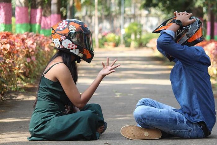 Photo of a couple wearing helmets, sitting on a pavement in a park [Image Credit: Professional QP]