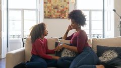 A woman holding hands with her daughter while sitting on couch [Photo: Kampus Production]