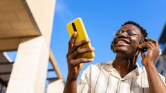 A young man relaxing outdoors listening to music using phone and headphones