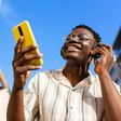 A young man relaxing outdoors listening to music using phone and headphones