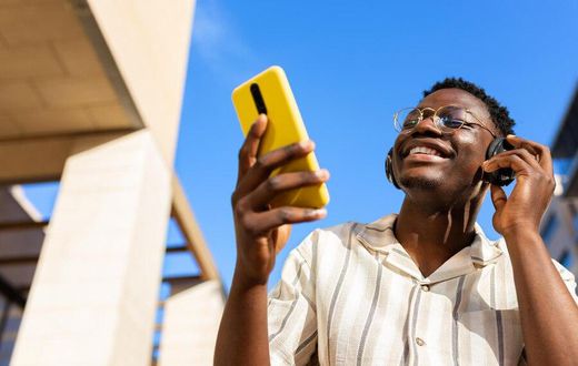A young man relaxing outdoors listening to music using phone and headphones