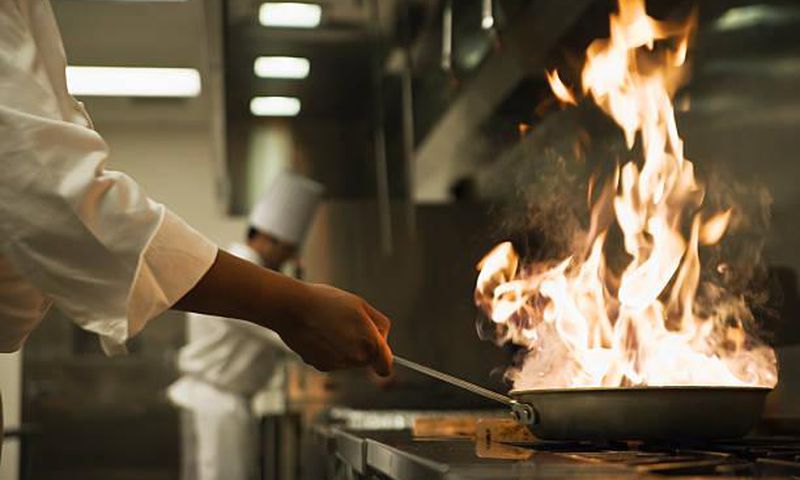 Chef holding flaming pan