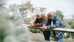Black father conversing with teenager near fence on farmland [Image: Any Lane]
