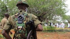 Kenya police officers stand guard as the bodies of suspected members of a Christian cult named as Good News International Church are exhumed in Shakahola forest in Kenya, April 22, 2023.Stringer/Reuters