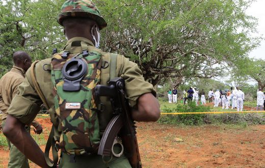 Kenya police officers stand guard as the bodies of suspected members of a Christian cult named as Good News International Church are exhumed in Shakahola forest in Kenya, April 22, 2023.Stringer/Reuters