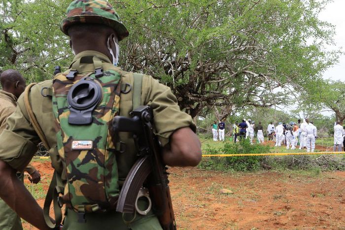 Kenya police officers stand guard as the bodies of suspected members of a Christian cult named as Good News International Church are exhumed in Shakahola forest in Kenya, April 22, 2023.Stringer/Reuters