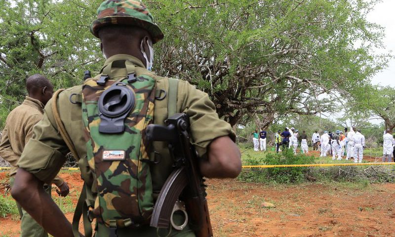 Kenya police officers stand guard as the bodies of suspected members of a Christian cult named as Good News International Church are exhumed in Shakahola forest in Kenya, April 22, 2023.Stringer/Reuters