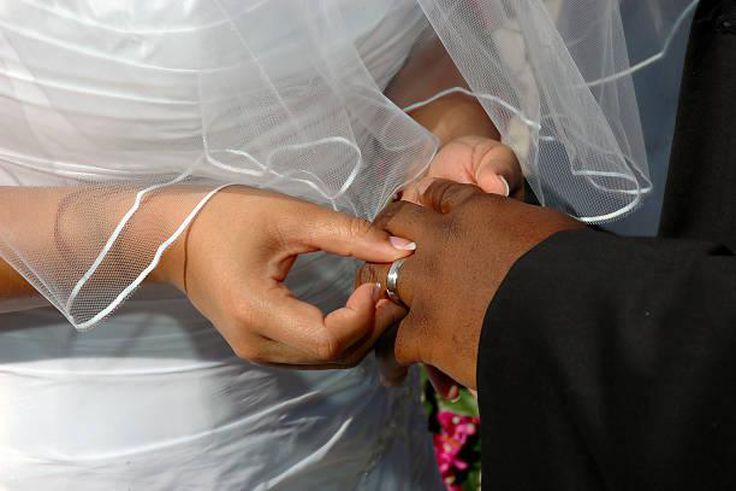 A bride inserting a ring on her grooms finger