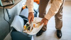 Man throwing left over food to a dustbin