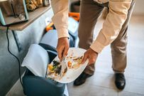 Man throwing left over food to a dustbin