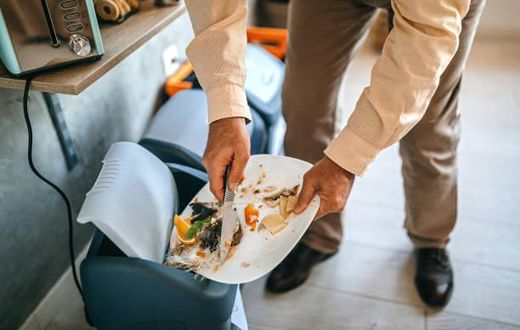 Man throwing left over food to a dustbin